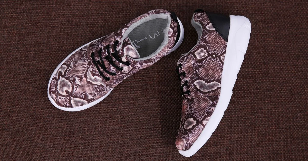 Vista superior de zapatillas de moda con estampado de serpiente sobre una superficie marrón texturizada, perfectas para conceptos de moda en calzado.