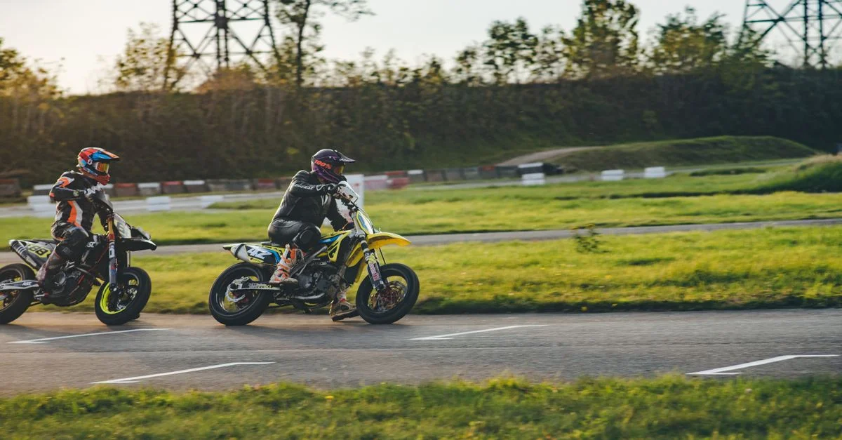 Deux motocyclistes faisant la course sur un circuit extérieur, montrant une action de sport motorisé palpitante.