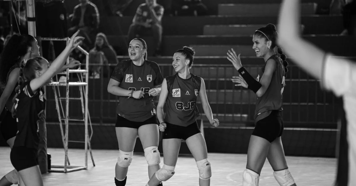 Foto en blanco y negro de un equipo femenino de voleibol celebrando después de un partido exitoso.