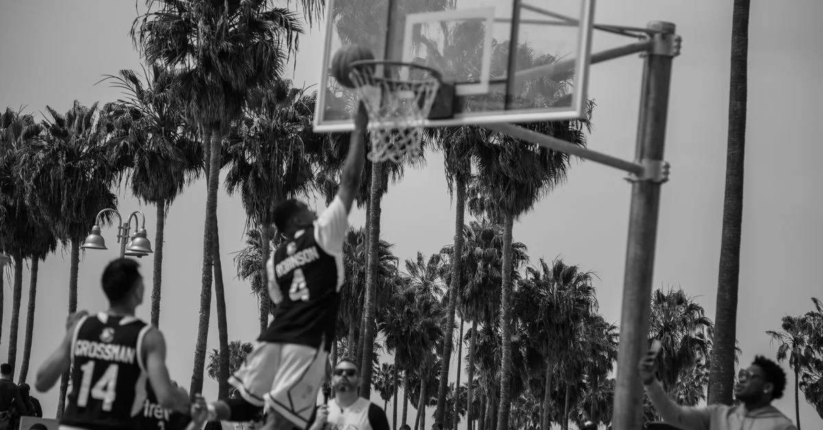 Juego dinámico de baloncesto al aire libre en blanco y negro que muestra atletismo en Los Ángeles.