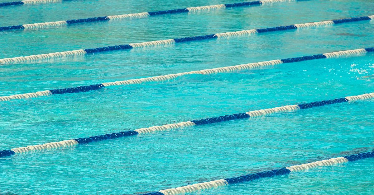 Vista de una piscina olímpica con separadores de carriles flotantes en agua tranquila.