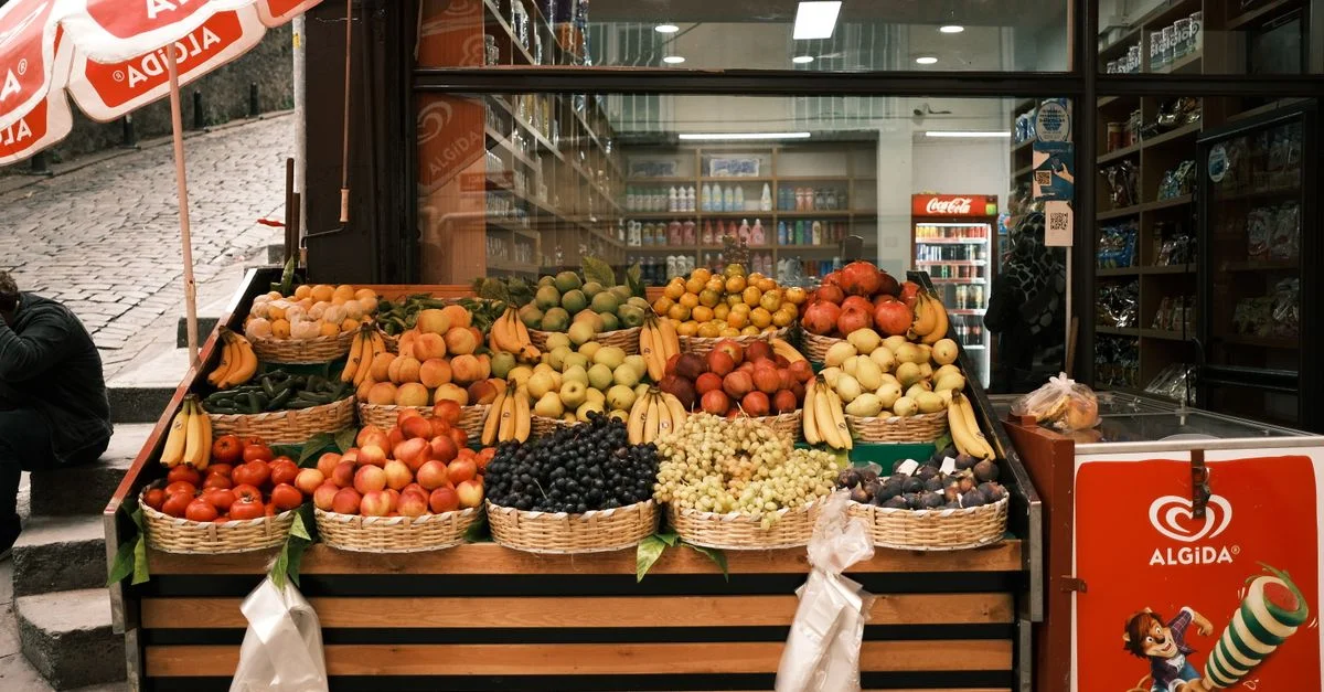 Exhibición vibrante de frutas surtidas en un puesto de mercado al aire libre con cestas de plátanos, uvas y más.