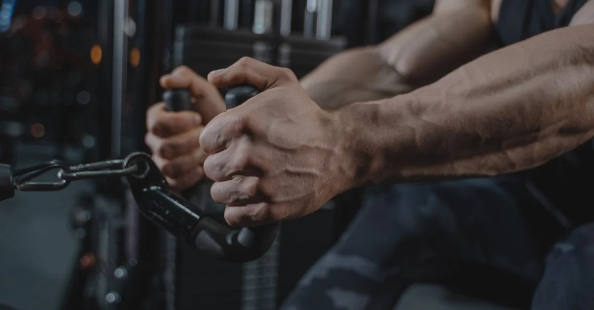 Hombre haciendo ejercicios con equipo de gimnasio, mostrando fuerza y determinación en un ambiente de fitness.