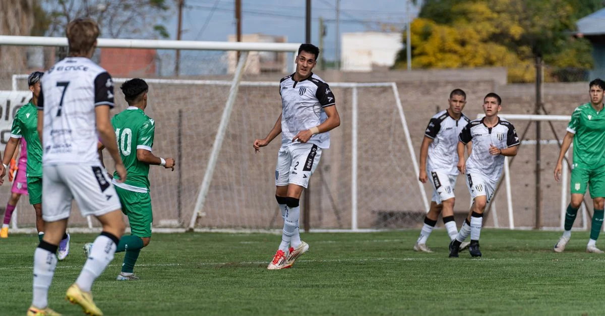 Jugadores participando en un partido de fútbol competitivo en un día despejado. Deportividad y trabajo en equipo en acción.