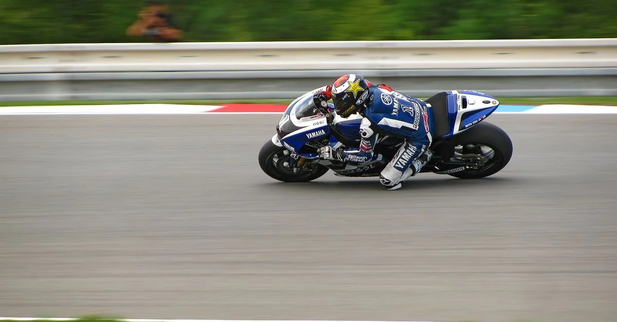 Toma dinámica de un piloto de motociclismo profesional acelerando en una pista durante una competición.