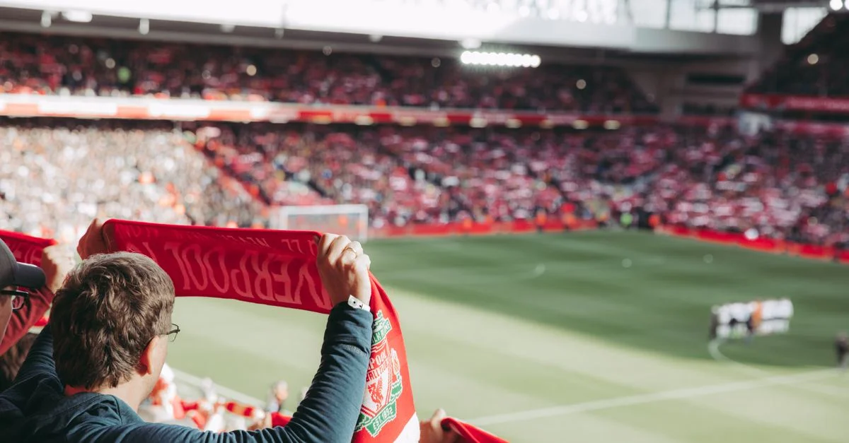 Aficionados apasionados del fútbol con bufandas en el Estadio de Anfield, capturando la emoción del juego.