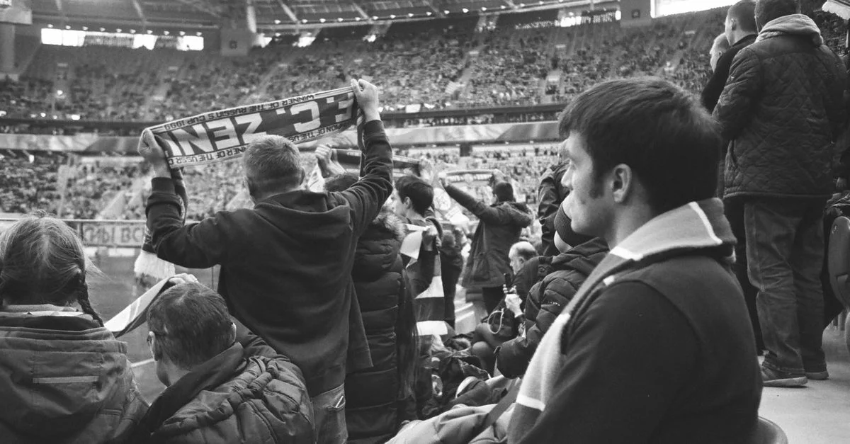 Aficionados emocionados reunidos en un estadio para ver un partido de fútbol en vivo.
